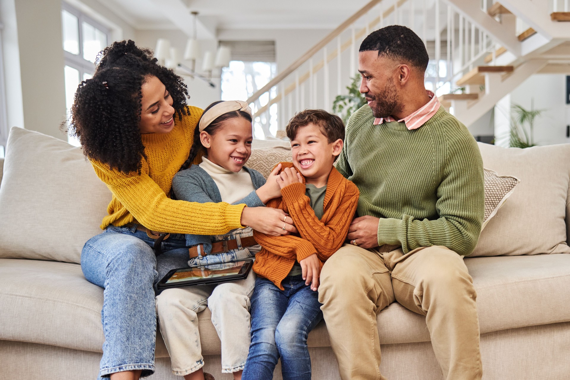 Laughing, family and children in home with winter fashion, parents or support with smile or foster care. Bonding, funny or happy kids with love, adoption and warm clothes to relax or play
